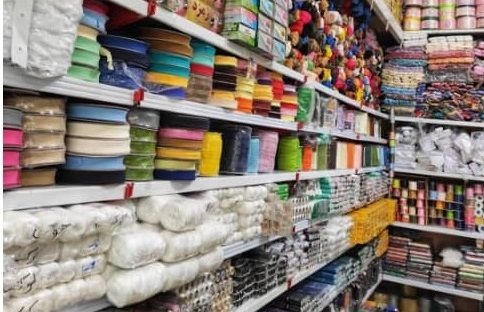 خرازی به فروشگاهی گفته می‌شود که انواع لوازم خیاطی، بافندگی، گلدوزی و صنایع دستی را عرضه می‌کند. این فروشگاه‌ها نقش مهمی در تأمین نیازهای خیاطان، طراحان لباس و علاقه‌مندان به هنرهای دستی دارند. در این مقاله از سری مقالات آموزشی، به بررسی مفهوم خرازی، تاریخچه آن و لوازمی که یک فروشگاه خرازی باید داشته باشد می‌پردازیم. برای تهیه ابزار باکیفیت، می‌توانید به فروشگاه ابزار دوخت صفری مراجعه کنید. تعریف خرازی خرازی در لغت به معنای فروشگاهی است که اقلام کوچک و متنوع مورد نیاز برای خیاطی و صنایع دستی را ارائه می‌دهد. این فروشگاه‌ها معمولاً محصولاتی مانند نخ، سوزن، دکمه، زیپ و پارچه‌های تزئینی را به مشتریان عرضه می‌کنند. تاریخچه خرازی در ایران خرازی‌ها در ایران قدمتی طولانی دارند و از گذشته به عنوان مراکز تأمین لوازم خیاطی و بافندگی شناخته می‌شدند. در بازارهای سنتی، مغازه‌های خرازی همیشه پر از رنگ و تنوع بودند و خیاطان برای خرید لوازم خیاطی به این مکان‌ها مراجعه می‌کردند. اهمیت خرازی در خیاطی فروشگاه‌های خرازی به دلیل ارائه ابزار و مواد اولیه متنوع، قلب تپنده صنعت خیاطی هستند. این فروشگاه‌ها به خیاطان کمک می‌کنند تا پروژه‌های خود را با کیفیت بالا و خلاقیت بیشتری به پایان برسانند. انواع فروشگاه‌های خرازی خرازی‌ها به دو نوع سنتی و مدرن تقسیم می‌شوند. خرازی‌های سنتی معمولاً در بازارها و محله‌های قدیمی یافت می‌شوند، در حالی که خرازی‌های مدرن، مانند فروشگاه ابزار دوخت صفری، محصولات را به صورت آنلاین و حضوری با تنوع بیشتری عرضه می‌کنند. لوازم خیاطی در خرازی یکی از مهم‌ترین دسته‌های محصولات خرازی، لوازم خیاطی است. این لوازم شامل سوزن، نخ، قیچی، متر خیاطی و صابون خیاطی می‌شود. این ابزار برای هر خیاط، چه مبتدی و چه حرفه‌ای، ضروری هستند. نخ و انواع آن در خرازی نخ‌های خیاطی در جنس‌ها و رنگ‌های مختلف در خرازی‌ها موجود هستند. نخ‌های پنبه‌ای، پلی‌استر و ابریشمی برای دوخت‌های دستی و ماشینی کاربرد دارند. انتخاب نخ مناسب تأثیر زیادی بر کیفیت دوخت دارد. دکمه و زیپ در خرازی دکمه‌ها و زیپ‌ها از پرکاربردترین اقلام خرازی هستند. دکمه‌های تزئینی و زیپ‌های رنگی می‌توانند به لباس‌ها جلوه‌ای خاص ببخشند. خرازی‌ها معمولاً این محصولات را در طرح‌ها و اندازه‌های متنوع ارائه می‌دهند. پارچه‌های تزئینی و نوارها پارچه‌های تزئینی مانند تور، مخمل و ساتن، همراه با نوارهای اریب و تزئینی، در خرازی‌ها یافت می‌شوند. این محصولات برای حاشیه‌دوزی و تزئین لباس‌ها و صنایع دستی استفاده می‌شوند. ابزار گلدوزی در خرازی گلدوزی یکی از هنرهای محبوب است که نیاز به ابزار خاص دارد. سوزن‌های گلدوزی، نخ‌های DMC، کارگاه گلدوزی و الگوهای آماده از جمله اقلامی هستند که در خرازی‌ها موجودند. لوازم بافندگی در خرازی علاقه‌مندان به بافندگی می‌توانند میل و قلاب بافندگی، کامواهای رنگی و کتاب‌های آموزشی را از خرازی‌ها تهیه کنند. این محصولات برای بافت شال، کلاه و لباس کاربرد دارند. قیچی‌های خیاطی و کاربردشان قیچی‌های خیاطی در انواع مختلف، از جمله قیچی دالبر و قیچی معمولی، در خرازی‌ها عرضه می‌شوند. در خرید لوازم دوخت، انتخاب قیچی با تیغه‌های تیز و ارگونومیک اهمیت زیادی دارد. متر خیاطی و ابزار اندازه‌گیری متر خیاطی، خط‌کش و گونیا از ابزارهای اندازه‌گیری پرکاربرد در خرازی‌ها هستند. این ابزارها به خیاطان کمک می‌کنند تا برش و دوخت را با دقت بیشتری انجام دهند. سوزن و جاسوزنی در خرازی سوزن‌های خیاطی در اندازه‌ها و انواع مختلف برای دوخت دستی و ماشینی در خرازی‌ها موجودند. جاسوزنی‌های مغناطیسی نیز برای سازماندهی سوزن‌ها بسیار کاربردی هستند. چرخ خیاطی و لوازم یدکی برخی خرازی‌ها چرخ خیاطی‌های خانگی و لوازم یدکی مانند ماسوره، سوزن چرخ و روغن چرخ خیاطی را عرضه می‌کنند. برای خرید لوازم یدکی خیاطی، خرازی‌های معتبر گزینه‌ای مناسب هستند. مواد اولیه صنایع دستی خرازی‌ها علاوه بر خیاطی، مواد اولیه برای ساخت زیورآلات، نمددوزی و چرم‌دوزی را نیز ارائه می‌دهند. مهره‌ها، چرم مصنوعی و ابزار نمددوزی از جمله این محصولات هستند. نقش خرازی در نمددوزی نمددوزی یکی از هنرهای پرطرفدار است که نیاز به پارچه نمد، قالب‌های برش و سوزن‌های مخصوص دارد. خرازی‌ها این اقلام را با تنوع رنگی بالا عرضه می‌کنند. خرازی و چرم‌دوزی برای چرم‌دوزی، خرازی‌ها ابزارهایی مانند سوزن‌های ضخیم، نخ موم‌زده و چرم مصنوعی را فراهم می‌کنند. این محصولات برای ساخت کیف و اکسسوری‌های چرمی ضروری هستند. خرازی آنلاین و مزایای آن خرازی‌های آنلاین امکان خرید آسان و مقایسه محصولات را فراهم می‌کنند. این فروشگاه‌ها معمولاً تنوع بیشتری دارند و محصولات را به سراسر کشور ارسال می‌کنند. نکات مهم در خرید از خرازی هنگام خرید از خرازی، به کیفیت محصولات، برند و قیمت توجه کنید. همچنین، بررسی نظرات مشتریان می‌تواند به انتخاب بهتر کمک کند. خرازی‌های معتبر معمولاً محصولات باکیفیت‌تری ارائه می‌دهند. نگهداری از لوازم خرازی لوازم خیاطی و صنایع دستی باید در جای خشک و دور از رطوبت نگهداری شوند. قیچی‌ها را پس از استفاده تمیز کنید و سوزن‌ها را در جاسوزنی نگه دارید تا از گم شدن یا زنگ‌زدگی جلوگیری شود. خرازی و آموزش خیاطی بسیاری از خرازی‌ها کتاب‌ها و الگوهای آموزشی برای خیاطی و صنایع دستی ارائه می‌دهند. این منابع برای یادگیری تکنیک‌های جدید و بهبود مهارت‌ها بسیار مفید هستند. خرازی و حمایت از تولید داخلی خرازی‌ها با عرضه محصولات تولید داخل، به حمایت از تولیدکنندگان ایرانی کمک می‌کنند. خرید از این فروشگاه‌ها می‌تواند به رشد اقتصاد محلی و حفظ هنرهای سنتی کمک کند. معرفی فروشگاه ابزار دوخت صفری فروشگاه ابزار دوخت صفری با بیش از 30 سال تجربه فنی در زمینه تولید و فروش انواع البسه و تعمیر و فروش انواع ماشین‌آلات دوخت، در دهه سوم فعالیت خود تعمیر، تأمین و توزیع تمامی ملزومات دوخت را در حوزه‌های مختلف مانند انواع پوشاک، کیف و کفش، مبلمان، صندلی اداری و سایر زمینه‌های مرتبط با دوخت و دوز در برنامه خود قرار داده است. این فروشگاه تمام محصولات و ملزومات دوخت را به قیمت عمده، از یک عدد تا هر تعداد که نیاز شما باشد، تأمین کرده و در محل به شما تحویل می‌دهد. اطلاعات تماس فروشگاه ابزار دوخت صفری برای ارتباط با فروشگاه ابزار دوخت صفری، می‌توانید از اطلاعات زیر استفاده کنید: شماره‌های تماس: 02166222380 - 02166140358 آدرس: تهران، بزرگراه آیت‌الله سعیدی، خیابان معلم، شهرک ولیعصر (عج)، انتهای خیابان حیدری جنوبی، خیابان سیدالشهدا، پلاک 32 جدول محصولات پیشنهادی خرازی محصول کاربرد برند پیشنهادی قیمت تقریبی (تومان) نخ خیاطی دوخت دستی و ماشینی گوتزل 15,000 قیچی دالبر برش تزئینی پارچه بلتکس 250,000 زیپ فلزی دوخت لباس و کیف YKK 20,000 پارچه نمد نمددوزی و کاردستی داخلی 50,000 (متری) سوزن گلدوزی گلدوزی دستی DMC 30,000 (بسته) متر خیاطی اندازه‌گیری دقیق تایگر 10,000 سوالات متداول درباره خرازی خرازی چیست و چه محصولاتی عرضه می‌کند؟ خرازی فروشگاهی است که لوازم خیاطی، گلدوزی، بافندگی و صنایع دستی مانند نخ، سوزن، دکمه و پارچه‌های تزئینی را ارائه می‌دهد. آیا خرازی‌ها لوازم چرم‌دوزی هم دارند؟ بله، خرازی‌ها ابزار چرم‌دوزی مانند سوزن‌های ضخیم، نخ موم‌زده و چرم مصنوعی را عرضه می‌کنند. چگونه از لوازم خرازی نگهداری کنیم؟ لوازم را در جای خشک نگه دارید، قیچی‌ها را تمیز کنید و سوزن‌ها را در جاسوزنی قرار دهید تا از زنگ‌زدگی جلوگیری شود. آیا خرازی‌های آنلاین قابل اعتماد هستند؟ بله، به شرطی که از فروشگاه‌های معتبر با نظرات مثبت خرید کنید. بررسی نظرات مشتریان می‌تواند به انتخاب کمک کند. چه مارکی برای نخ خیاطی مناسب است؟ برندهایی مانند گوتزل و DMC به دلیل کیفیت بالا برای دوخت دستی و ماشینی توصیه می‌شوند. آیا خرازی‌ها کتاب‌های آموزشی خیاطی دارند؟ بله، بسیاری از خرازی‌ها کتاب‌ها و الگوهای آموزشی برای خیاطی و صنایع دستی ارائه می‌دهند. نتیجه‌گیری خرازی‌ها به عنوان مراکز تأمین لوازم خیاطی و صنایع دستی، نقش مهمی در حمایت از هنرمندان و خیاطان دارند. با انتخاب یک خرازی معتبر مانند فروشگاه ابزار دوخت صفری، می‌توانید ابزار و مواد اولیه باکیفیت را به راحتی تهیه کنید. تنوع محصولات و خدمات این فروشگاه‌ها، از نخ و سوزن گرفته تا چرخ خیاطی و لوازم چرم‌دوزی، نیازهای هر پروژه خلاقانه‌ای را برآورده می‌کند.